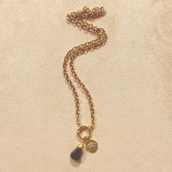 Gold chain necklace with two charms on a beige background